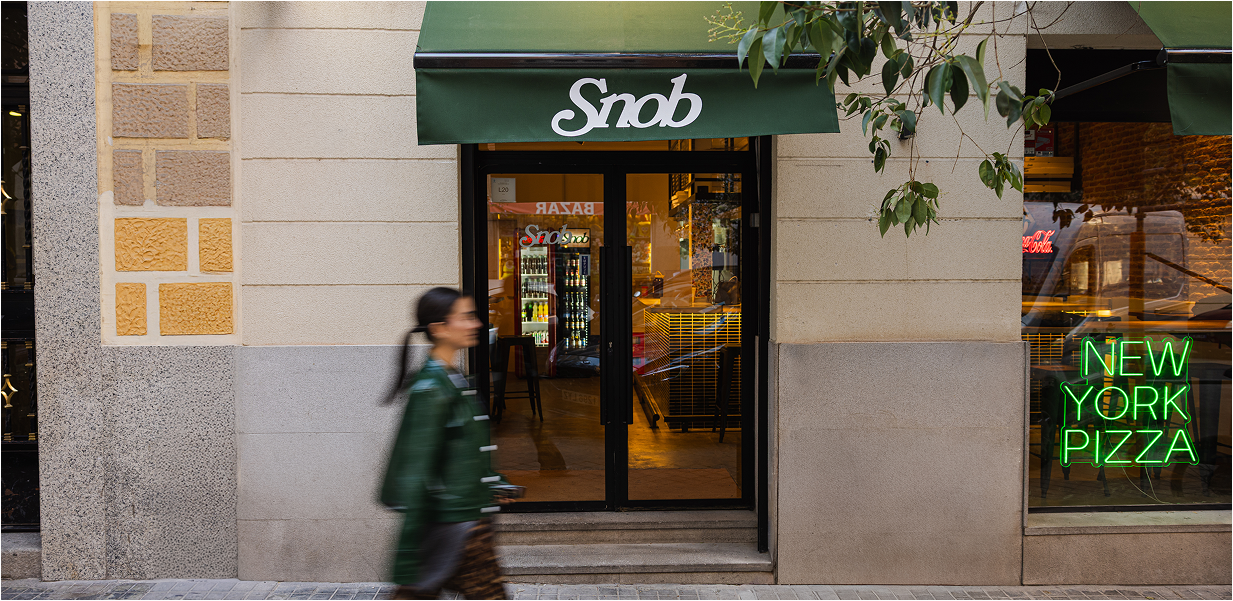Fachada de Snob en Madrid con el toldo verde y el letrero de New York Pizza